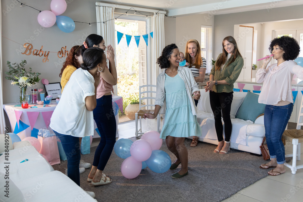 Obraz premium Diverse female friends celebrating baby shower in living room, dancing around pastel balloons