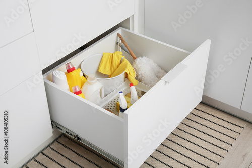 Drawer with cleaning supplies, basket and bucket in modern kitchen