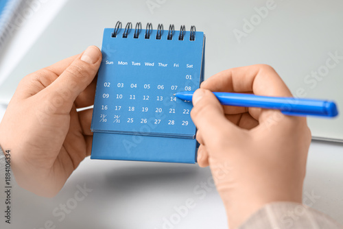 Female hands marking day on...