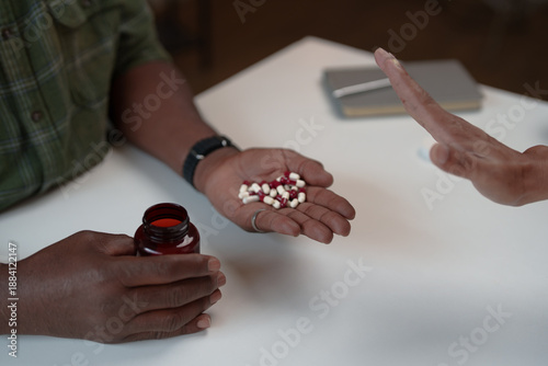 Tableau sur toile Person's hand presenting a handful of pills from a bottle, while another person'
