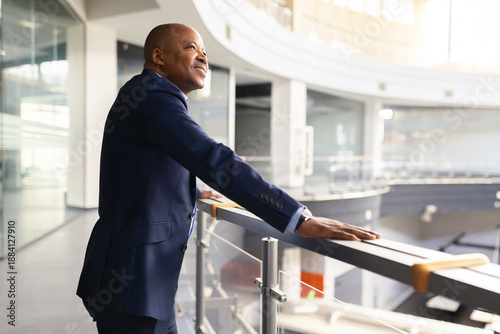 Valokuva Black mature businessman leaning on office balcony railing, looking ahead with c