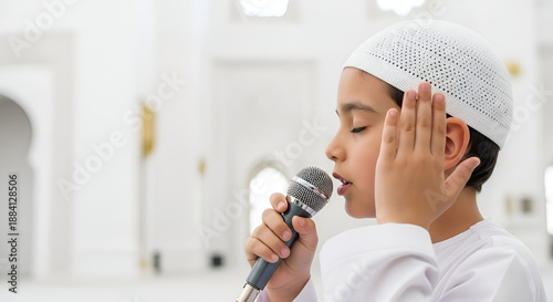 Young Muslim boy in traditional attire reverently recites Adhan or prayers into a microphone within a serene mosque, embodying a moment of deep faith and spiritual devotion