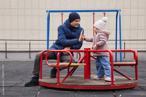 Father and daughter playing on a carousel, bonding and having fun