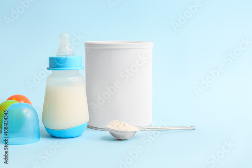 Tableau sur toile Feeding bottle with baby milk formula and rattle on color background