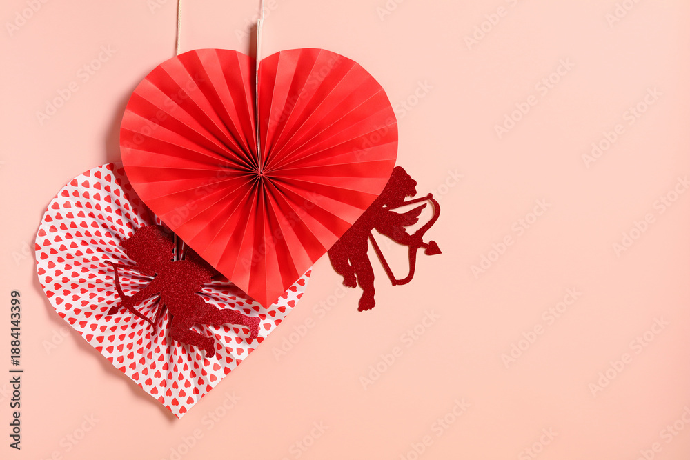 Obraz premium Happy Valentine's Day concept. Hanging paper hearts and Cupid silhouettes on a soft pink background for Valentine's Day.