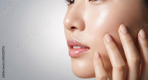 A young woman's smooth, glowing skin is gently touched by her fingers on her cheek, highlighting the results of a good skincare routine.