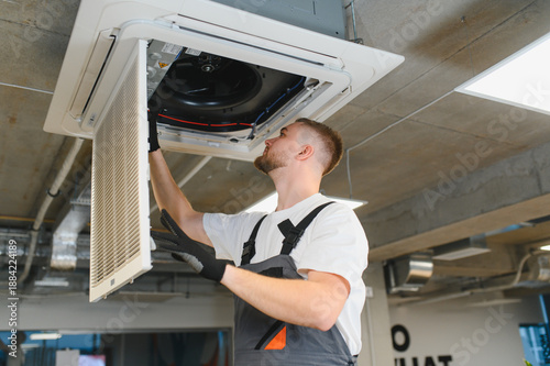 Slika na platnu Hvac technician servicing ceiling air conditioning unit filter