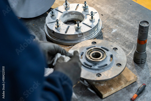 Vue sur une pièce mécanique et des composants métalliques posés sur un établi dans un atelier industriel, illustrant un environnement de fabrication et d’assemblage technique.