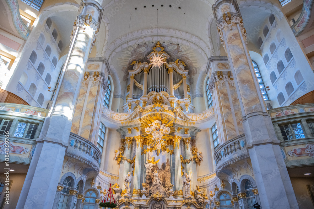 Fototapeta premium Visitors explore the interior of Frauenkirche in Dresden, Germany. The dome and ornate details showcase the church's architecture. Light filters through the windows, illuminating the space.