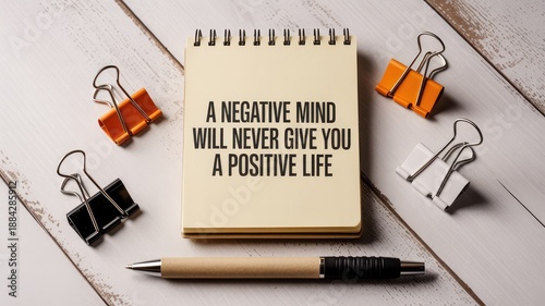 Inspirational quote on notepad surrounded by office supplies on a light wooden table top