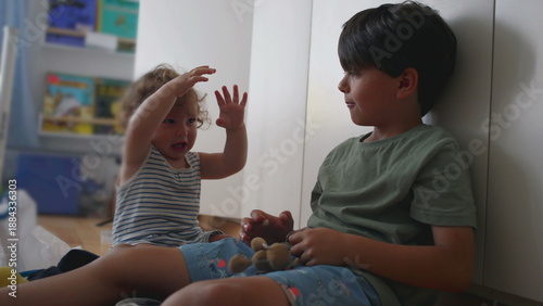 Tableau sur toile Baby flinches and laughs nervously as older brother dangles plush keychain above