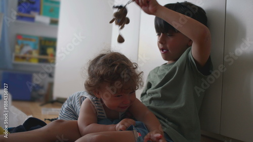 Foto Baby flinches and laughs nervously as older brother dangles plush keychain above