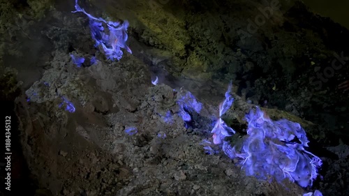 The blue flame of Kava-Ijen volcano burns on the dark earth, creating a stunning display of sulfuric gases at night. Java, Indonesia. Close-up of the famous blue flame phenomenon in the crater of Ijen