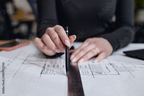 Fotografie Caucasian young adult woman drawing architectural plans using ruler and pen on d