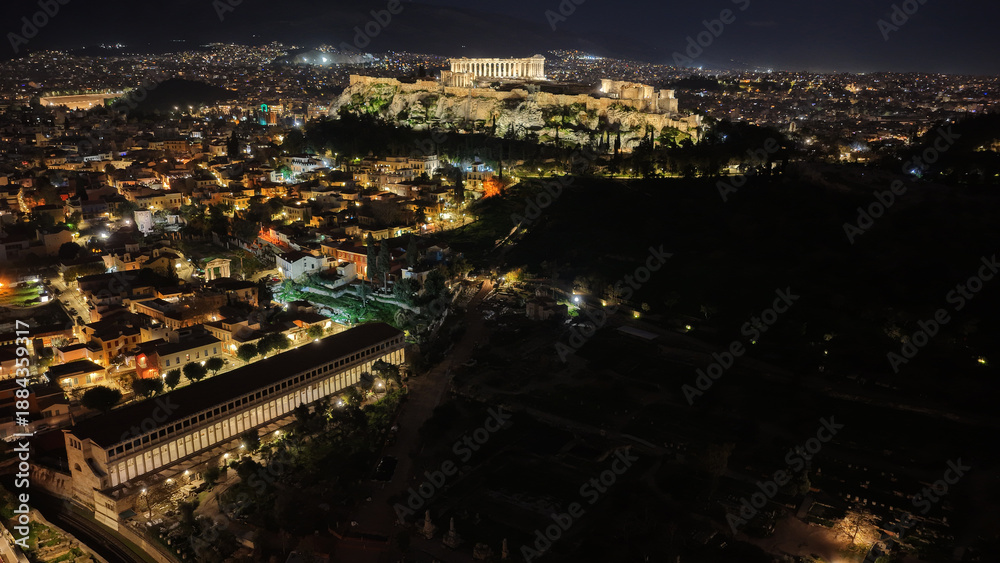 Obraz premium Aerial drone night shot of amazing illuminated ancient market of Athens or Agora featuring temple of Hephaestus, picturesque Plaka district and Acropolis hill, Attica, Greece