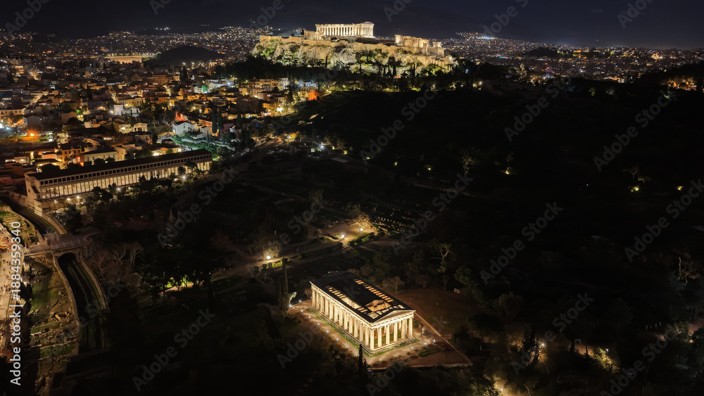 Fototapeta premium Aerial drone night shot of amazing illuminated ancient market of Athens or Agora featuring temple of Hephaestus, picturesque Plaka district and Acropolis hill, Attica, Greece