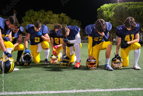 Foto American football players kneeling on the field, showing unity, prayer, or prote