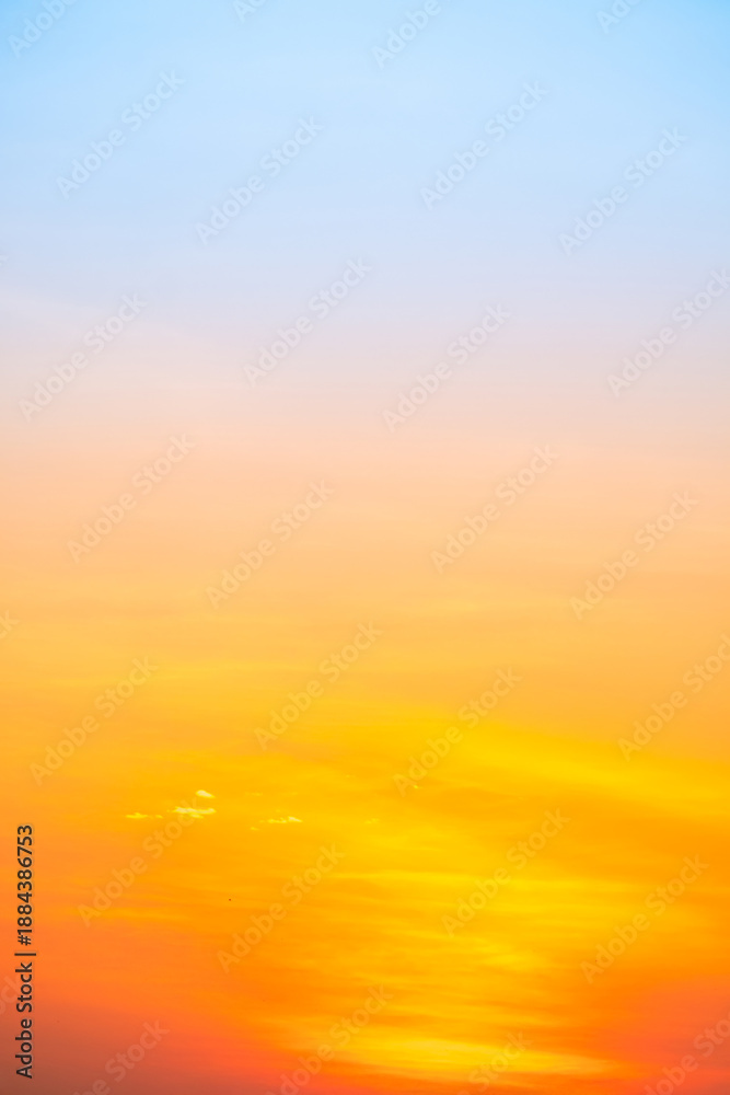 Obraz premium Sunset or sunrise sky with a vibrant gradient of orange, gold, and soft blue. Clear atmosphere with wispy clouds. Peaceful, natural light background. hope, freedom, new day Concepts, Vertical