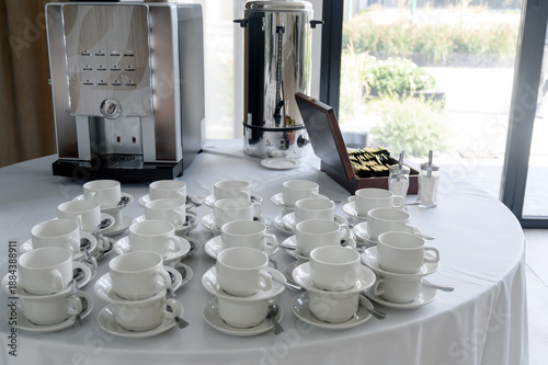 Coffee station with a professional coffee machine and white cups on a table