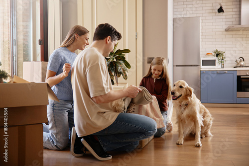 Tableau sur toile Family unpacking boxes with golden retriever in new kitchen
