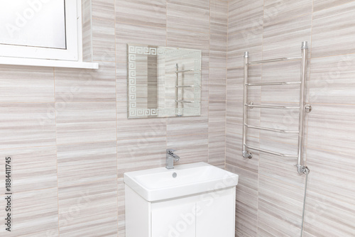 Fotografi Modern bathroom interior featuring a white sink, mirror, and towel warmer agains