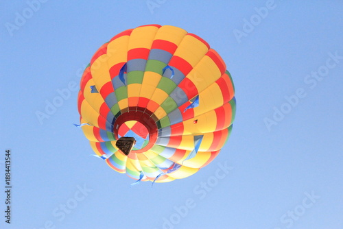 Φωτογραφία Vista desde abajo de un colorido globo aerostático con un vibrante patrón geométrico volando alto en un cielo azul despejado