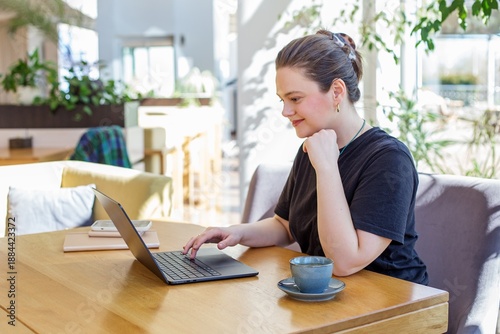 Young woman working remotely in sunny cafe