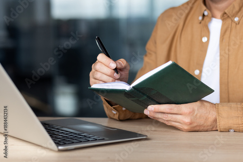 Canvas-taulu Man taking notes in a green diary, capturing ideas and planning tasks with a pen