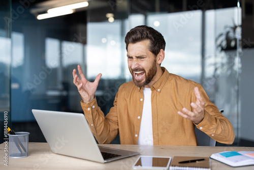 Εκτύπωση καμβά Frustrated man experiencing work problems and stress while screaming at a laptop