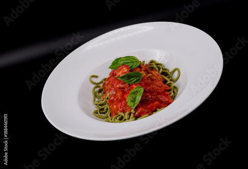Pasta italiana gourmet servida en plato blanco sobre fondo negro