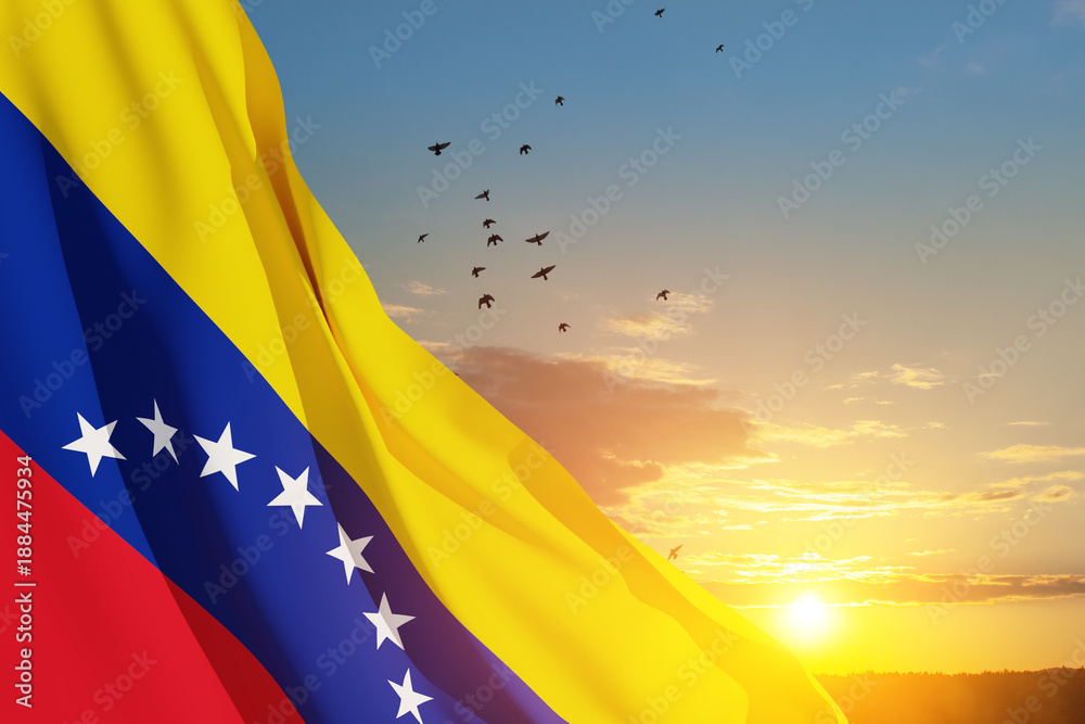 Obraz premium Venezuela flag on background of sunset sky with flying birds. Patriotic concept. Banner with place for text.