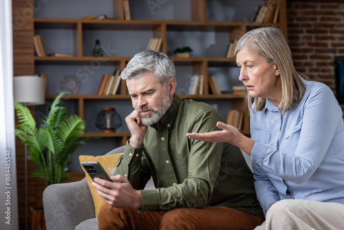 Fotografía Mature couple having a disagreement while the man is distracted by his smartphon