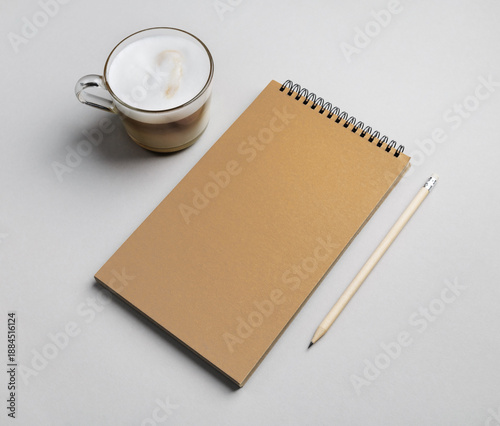 Blank sketchbook, coffee cup and pencil on gray paper surface.