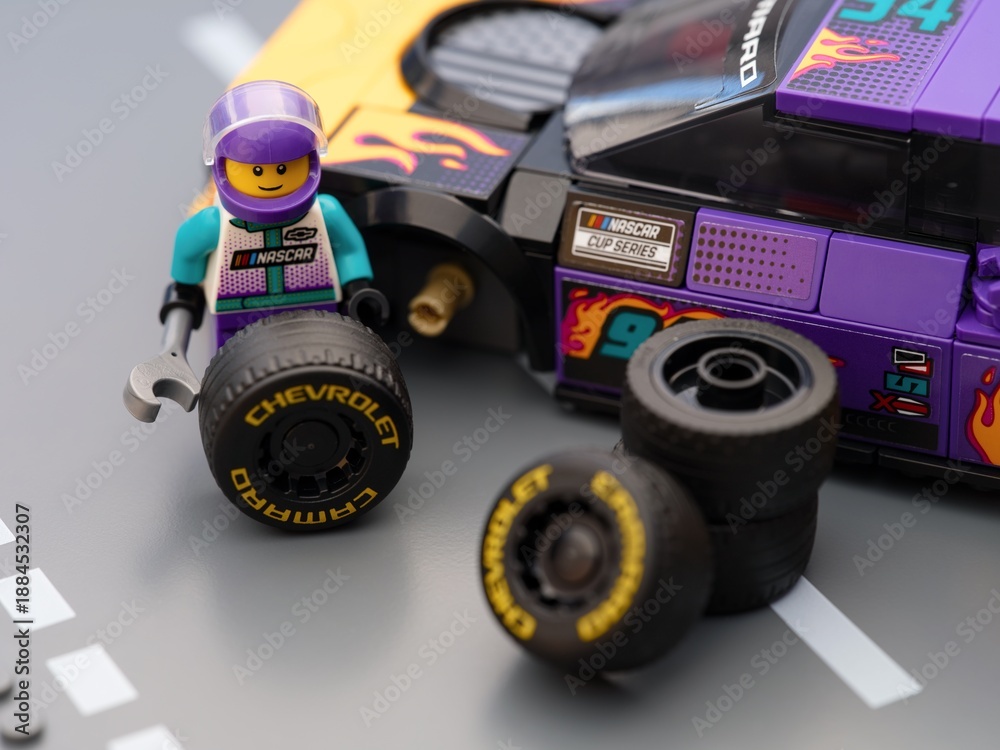 Fototapeta premium Tambov, Russian Federation - January 17, 2026 Lego driver minifigure changing wheel of a his Lego NASCAR Next Gen Chevrolet Camaro ZL car. LEGO Speed Champions.