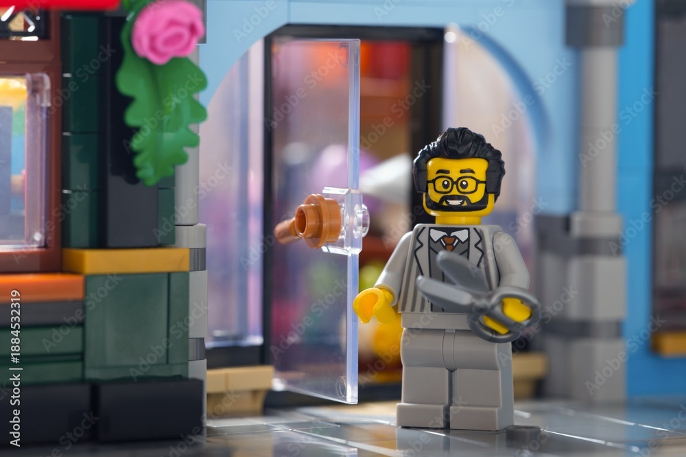 Fototapeta premium Tambov, Russian Federation - June 28, 2025 Lego barber minifigure with scissors standing near the entrance of his salon outdoors