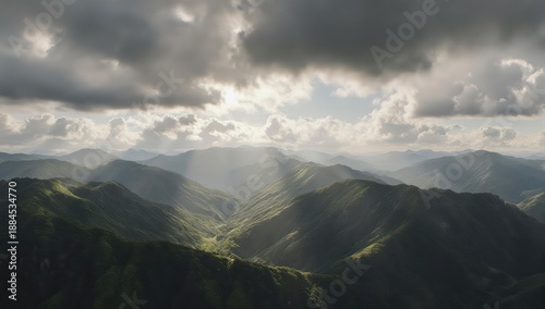 Sunlight breaks through clouds over a range of green, rolling mountains