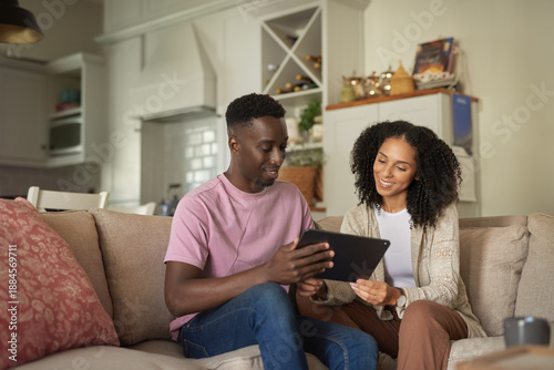 Smiling young multiracial couple using a tablet in their living room