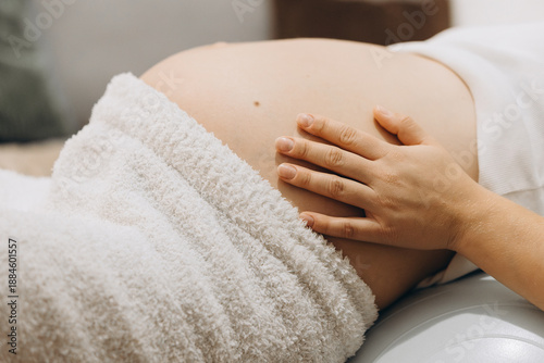Side View Of Pregnant Belly While Sitting On A Fitness Ball At Home. Concept Of Prenatal Wellness, Body Awareness, Maternity Care, And Preparation For Childbirth. Minimal And Intimate Indoor Scene Wit