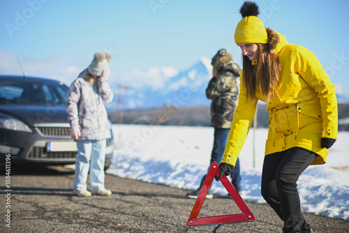 Bild auf Leinwand Family experiencing a vehicle breakdown on a wintry road, placing a warning tria