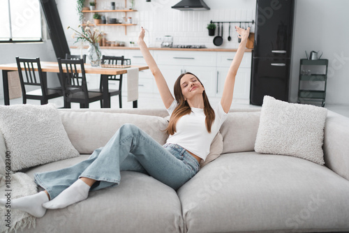 Apartment, woman and happy in portrait on sofa with peaceful, security or mortgage freedom. Young person, relax and smile in living room for comfortable break, insurance or wellness in home