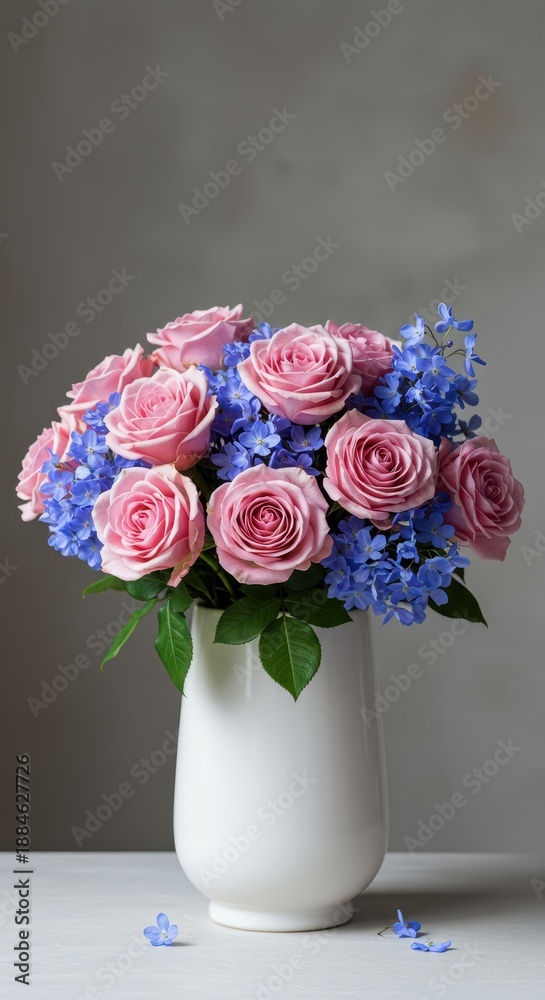 Fototapeta premium A vibrant arrangement featuring soft pink roses mixed with delicate blue blooms, presented beautifully in a clean white ceramic vase on a surface, vase, stem, blossom