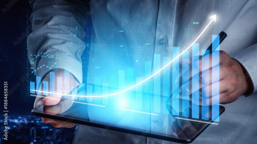 Obraz premium A businessman holds a tablet displaying financial data charts and graphs, representing growth in a rapidly changing market amid a nighttime city backdrop. Copula