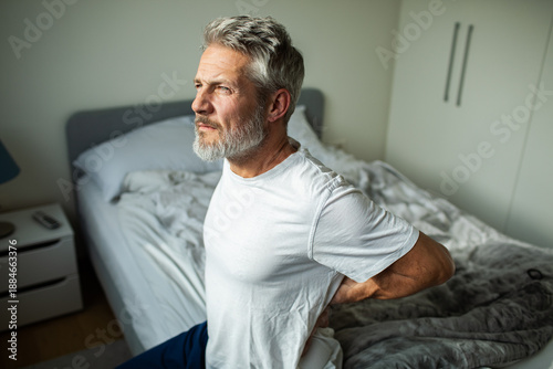Fotografía Middle-aged man with lower back pain in bedroom