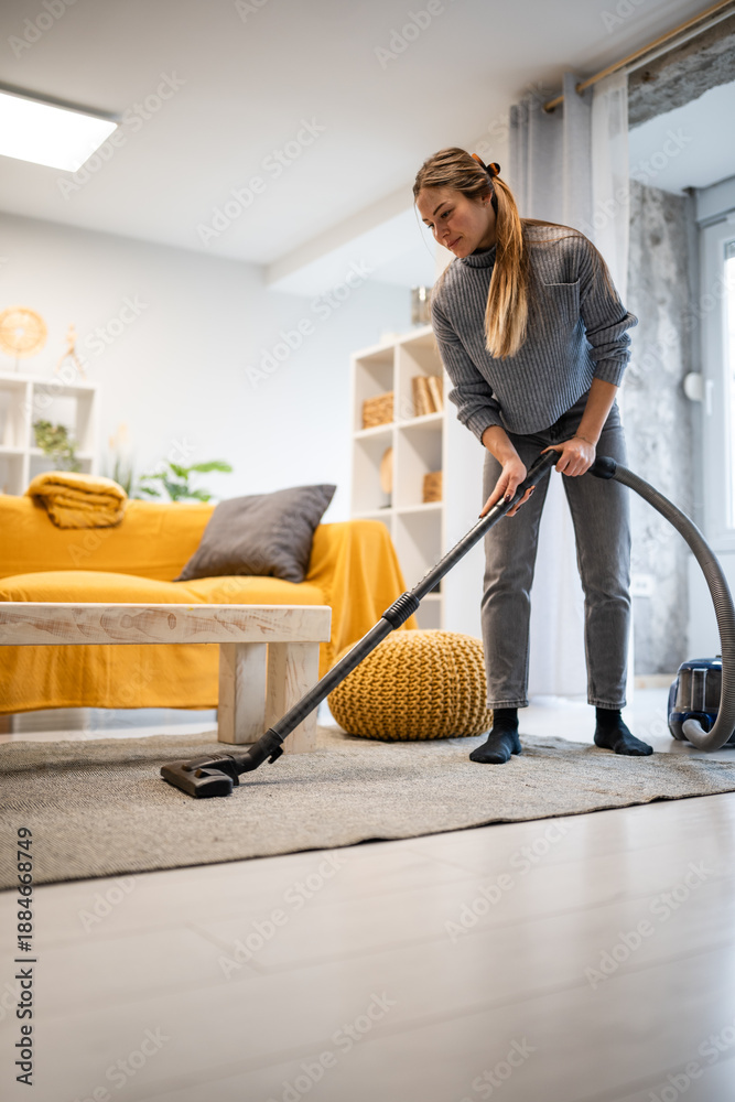 Fototapeta premium Woman vacuuming living room floor for clean home