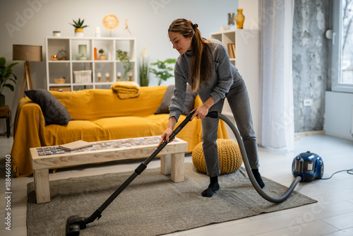 Bild auf Leinwand Woman vacuuming living room carpet doing housework