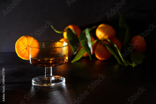 Elegant Glass With Orange Slice On Dark Surface, Fresh Oranges In Background