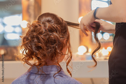 Foto Hairdresser making updo coiffure to brown haired girl