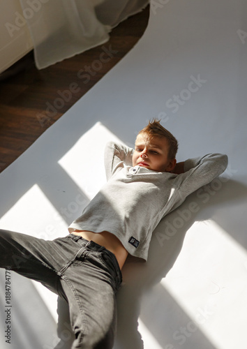 Young boy lying on the floor indoors. Child resting on the floor in a home environment. Casual lifestyle scene with a kid relaxing inside a room