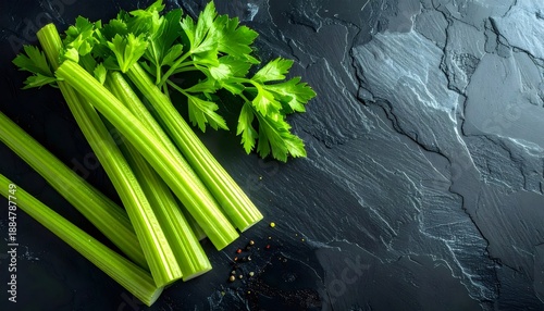 Fresh green celery stalks on dark slate background