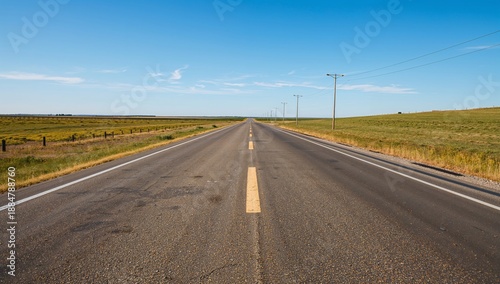 Open Road Stretches Across Flat Landscape Under Clear Blue Sky in a Rural Are...